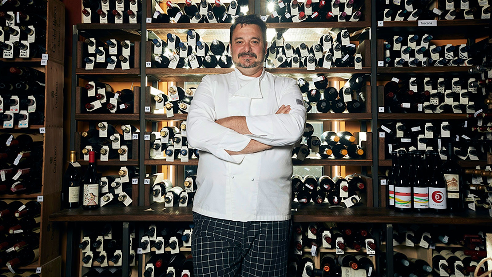 Ristorante Bilacus owner Aurelio Gandola in front of a wall of wine.